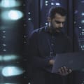 Person in datacenter holding a laptop.